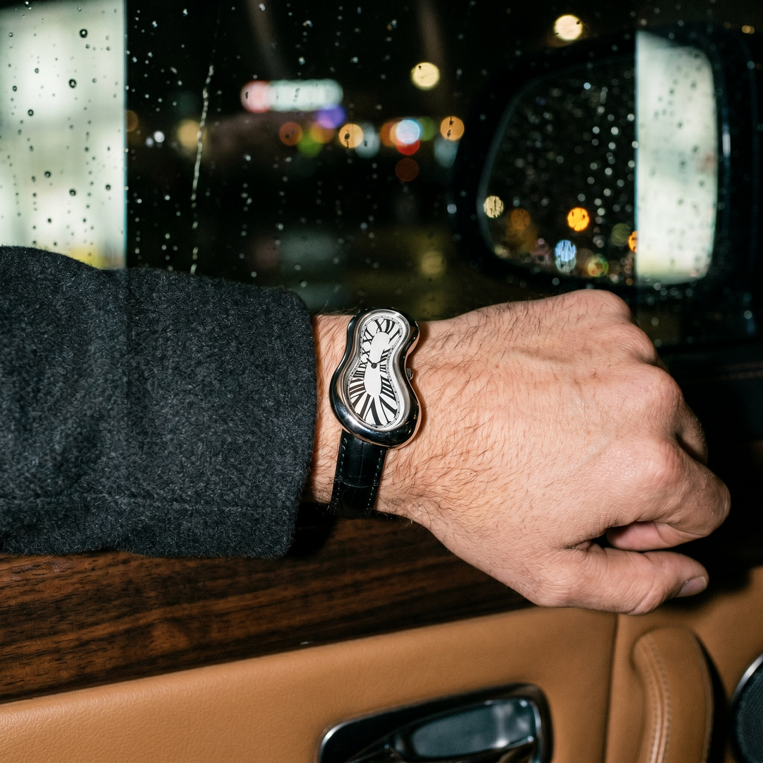 Silver warped Ombré Noir watch worn inside a car on a rainy night
