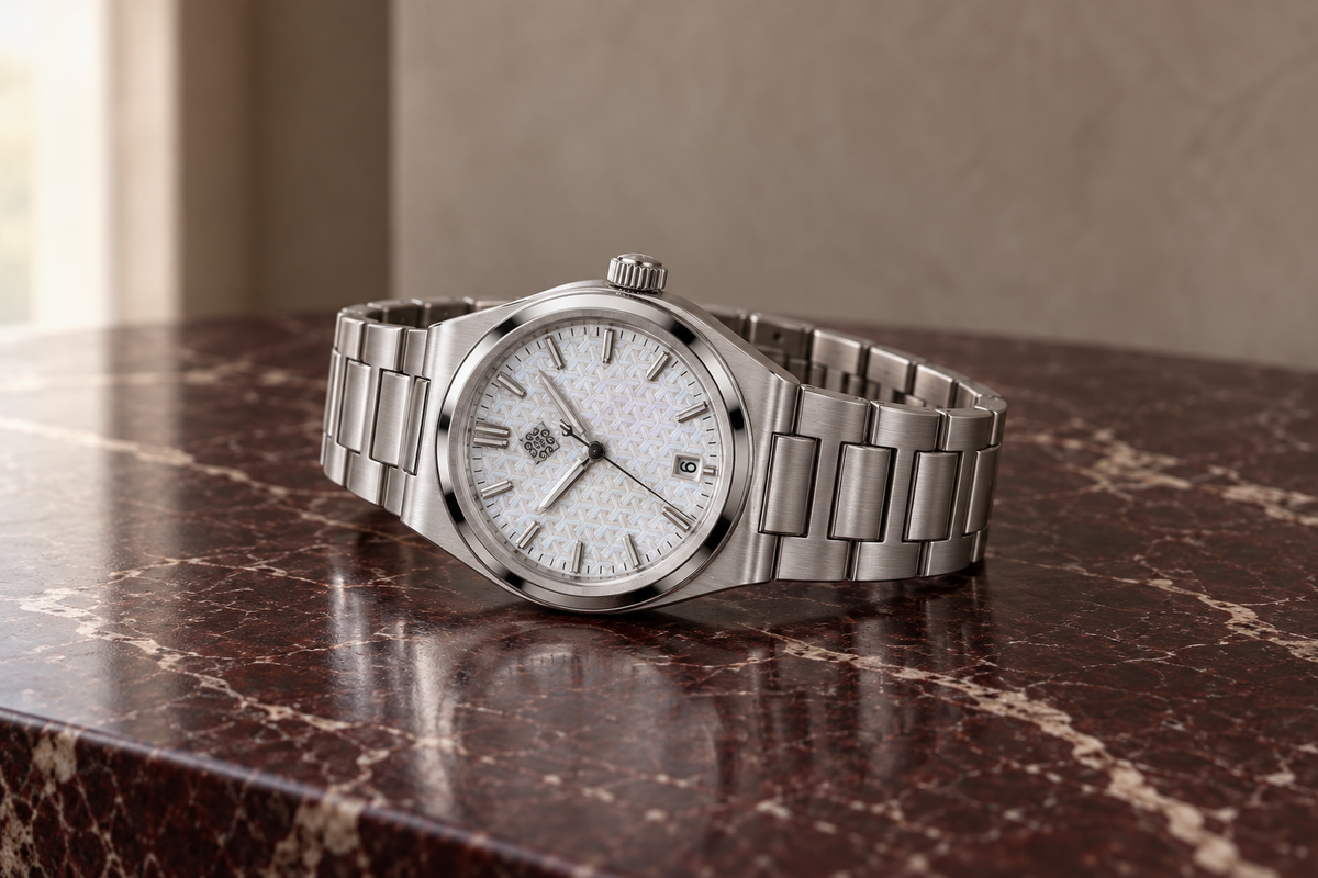 Silver automatic watch resting on burgundy marble editorial campaign