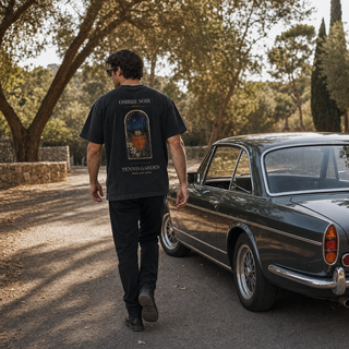 Back of black Tennis Garden T-Shirt worn outdoors beside a dark classic car