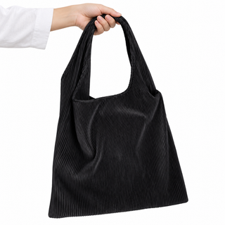 Hand holding the Plissé black pleated shoulder tote for scale