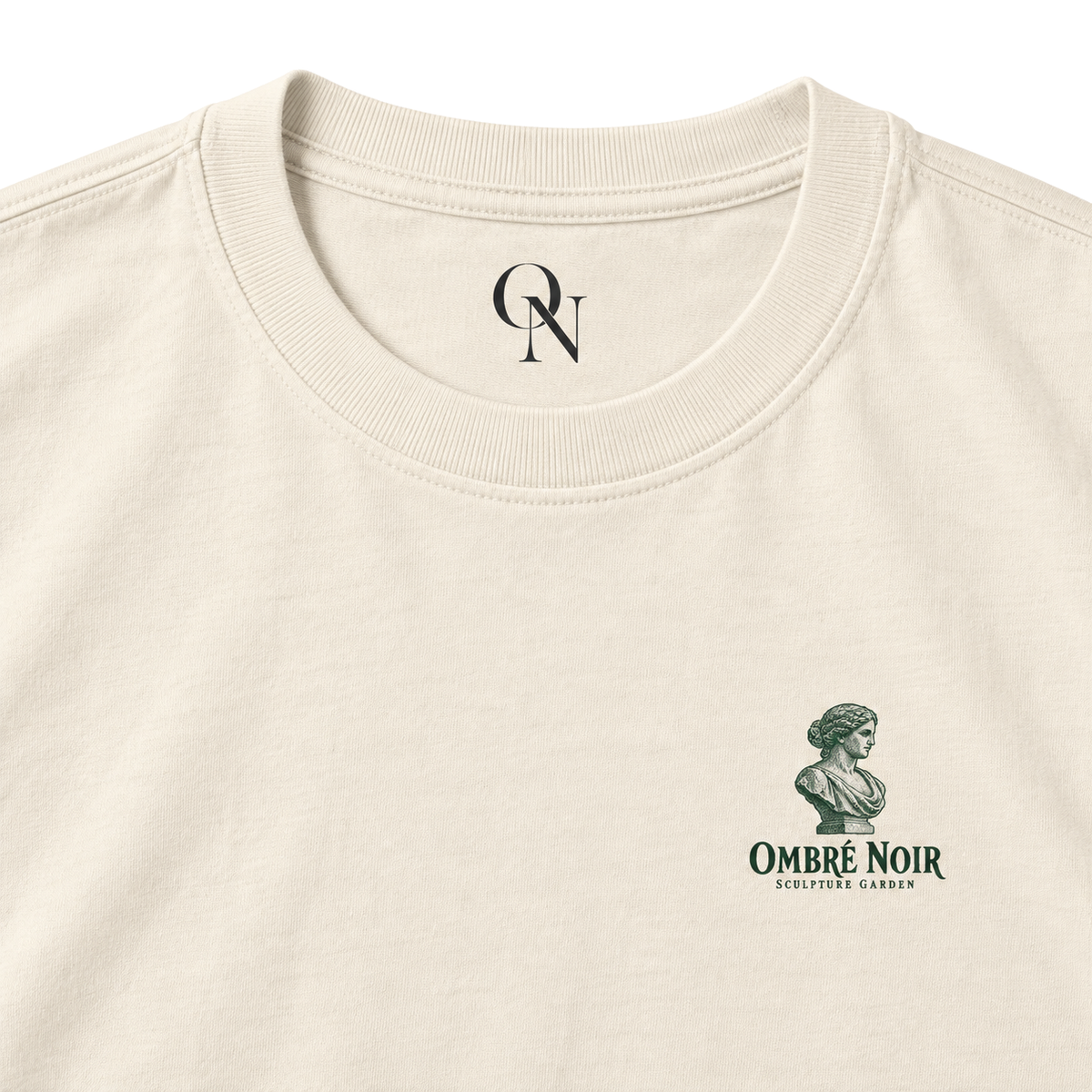 The Sculpture Garden Faded Cream tee detail: collar, inner-neck mark and green bust chest print